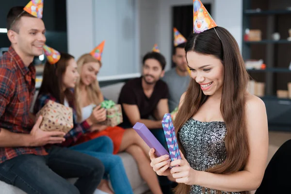 Fiesta en honor al cumpleaños. La cumpleañera abre el regalo. Ella se alegra de recibir un regalo . — Foto de Stock