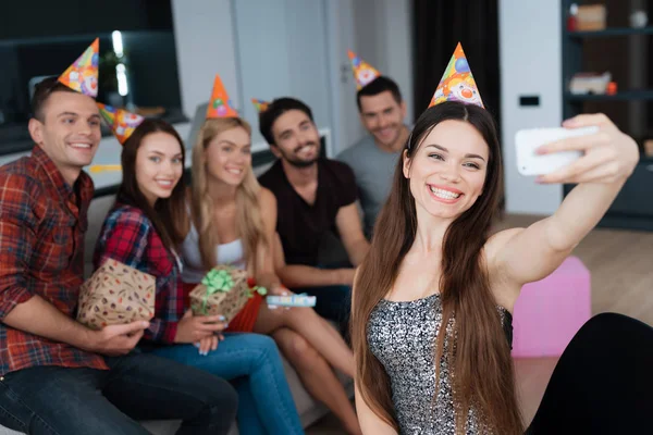 Das Geburtstagskind macht ein Selfie mit Gästen auf der Couch. Sie alle lächeln und posieren für ein Foto. — Stockfoto