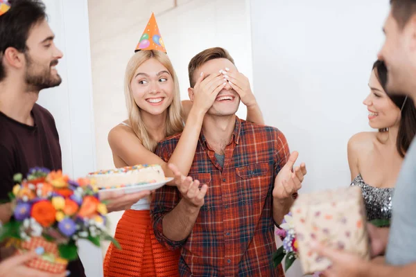 Flickan har förberett killen en överraskning för födelsedag. Hon avslutade hans ögon av händer. — Stockfoto