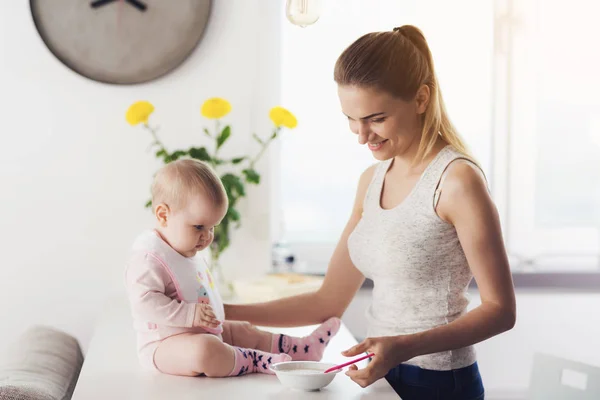 Mamá y el bebé en la cocina. La mujer va a alimentar al bebé con comida para bebés. . —  Fotos de Stock