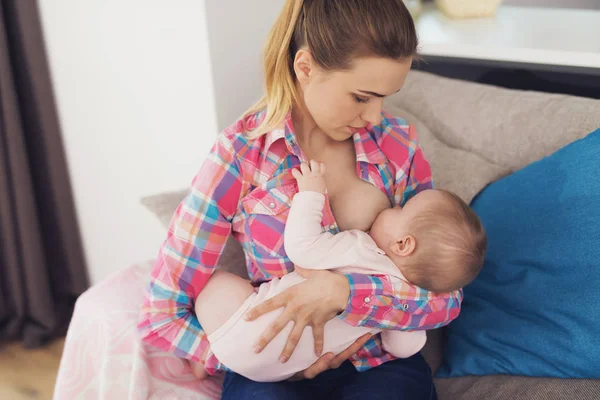 Mamma matar barnet med bröstet. Hon håller barnet i famnen. — Stockfoto