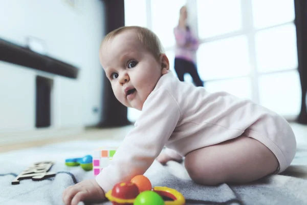 Dítě je bez dozoru. Zatímco žena mluví do telefonu, její dítě prochází na podlaze a hraje. — Stock fotografie