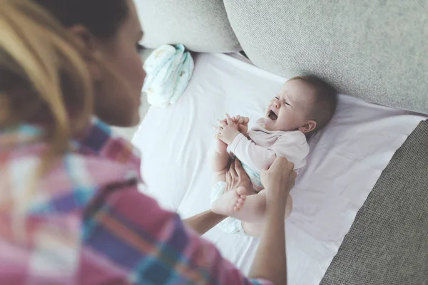 Жінка розбуджує маленьку дитину на дивані. Дитина розплакалася. Жінка намагається заспокоїти дитину. . — стокове фото