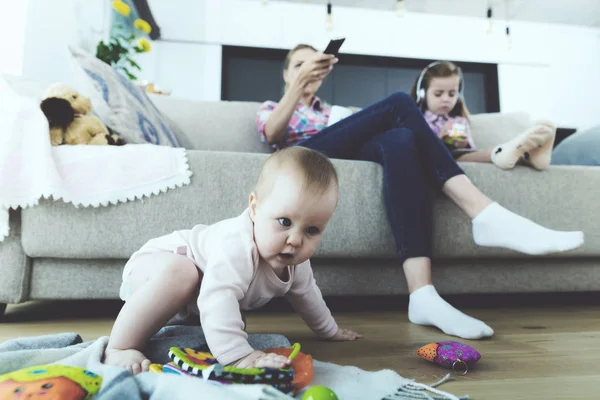 Женщина и девушка сидят на диване и не следуют за ребенком. Ребенок сидит на полу . — стоковое фото