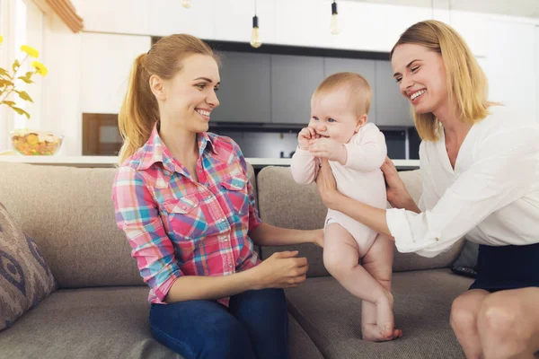 The woman came home and hugs her baby. A nurse is sitting next to her, who watched the children all day. — Stock Photo, Image