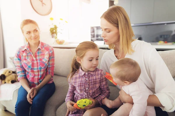 The woman came home and hugs her children. A babysitter is sitting next to them. — Stock Photo, Image