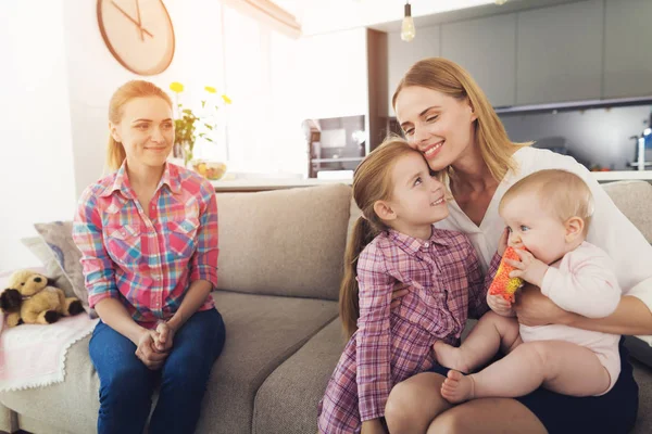 The woman came home and hugs her children. A babysitter is sitting next to them. — Stock Photo, Image