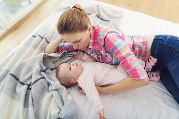 Una mujer está acostada en la cama junto al bebé. Ella pondrá al bebé en la cama. . —  Fotos de Stock