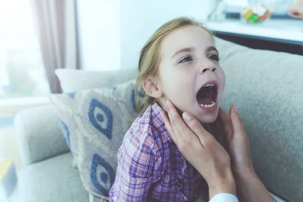 Девочка заболела, к ней подошел врач и осмотрел горло. . — стоковое фото
