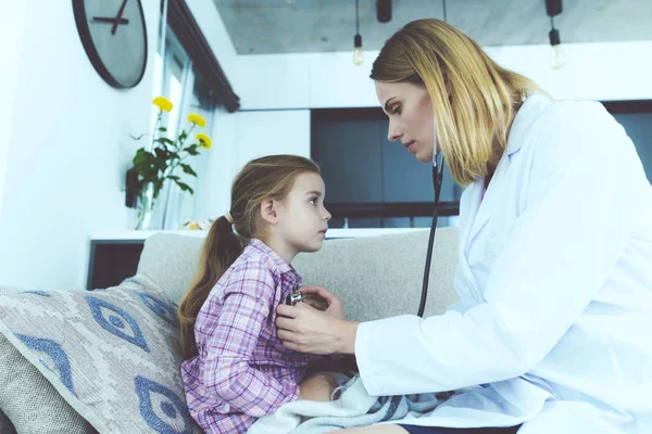 Küçük kız hastalandı. Bir doktor ona geldi ve onu bir stetoskop ile dinledi. — Stok fotoğraf