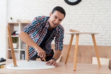 Genç adam onun sehpa ve tabureler kat kendisine çalışır.