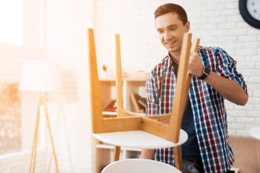 Genç adam onun sehpa ve tabureler kat kendisine çalışır.