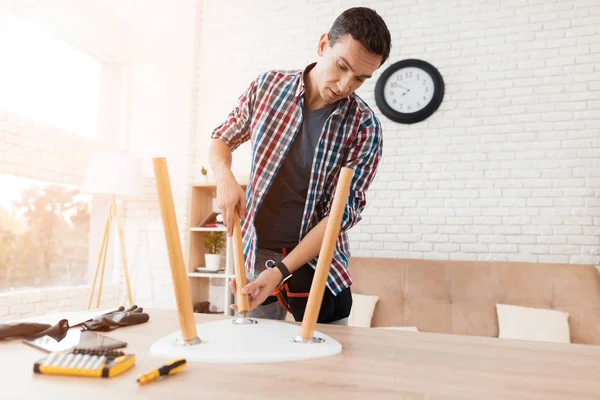 The young man tries himself to fold his coffee table and stools. — Stock Photo, Image