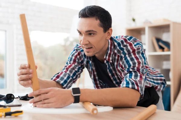 De jonge man probeert zichzelf te vouwen zijn koffie tafel en krukjes. — Stockfoto