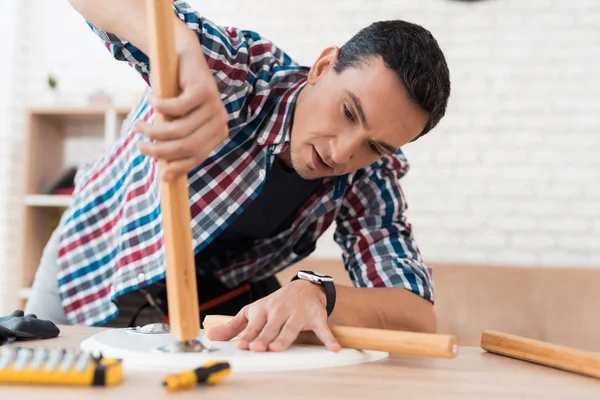 The young man tries himself to fold his coffee table and stools. — Stock Photo, Image