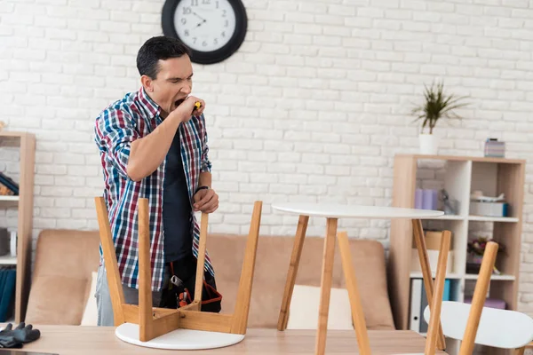 El joven trata de doblar su mesa de café y taburetes . — Foto de Stock