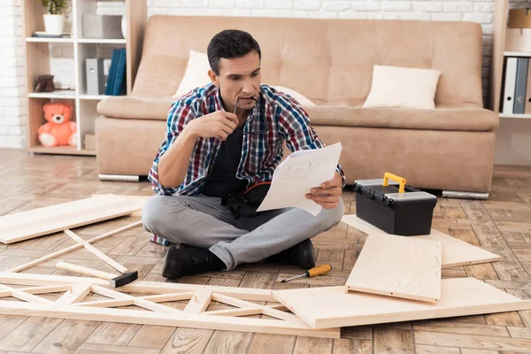 Den unge mannen försöker själv att vika sin bokhylla. — Stockfoto