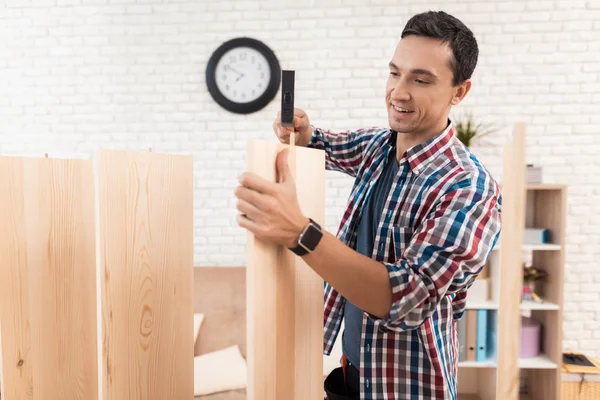 The young man tries himself to fold his bookcase. — Stock Photo, Image