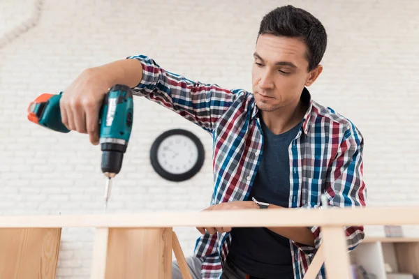 The young man tries himself to fold his bookcase. — Stock Photo, Image