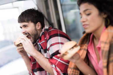 Genç bir çift mobil bir lokantada emrettiler hamburger yiyor