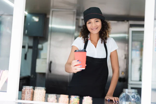 Vendedor feminino atraente posando em um restaurante móvel com uma caneca de café nas mãos — Fotografia de Stock