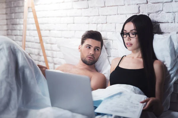 Mädchen und Mann liegen im Bett. Mädchen am Laptop im Bett. das Mädchen achtet nicht auf ihren Freund. — Stockfoto