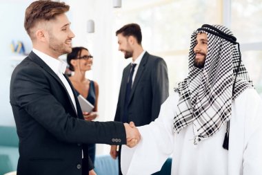 Arap giysili bir adam ve bir adam bir takım elbise eller titriyor.