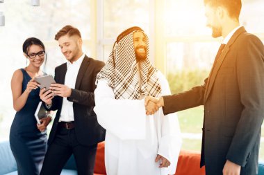 Arap giysili bir adam ve bir adam bir takım elbise eller titriyor.