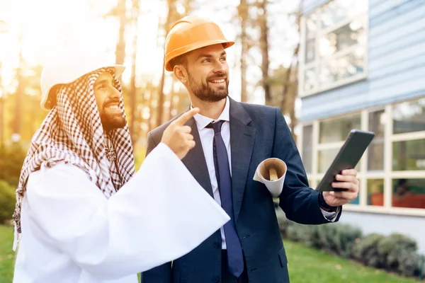 L'uomo col casco mostra il piano di costruzione di un uomo d'affari arabo. . — Foto Stock