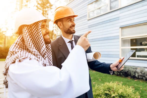 Человек в шлеме показывает план строительства для арабского бизнесмена . — стоковое фото