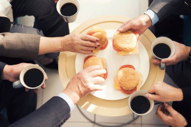 Bir tabak ve dört el dört hamburger yakın çekim fotoğraf. İnsanlar kahve tutuyorsun.