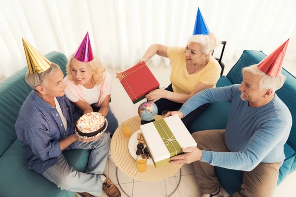 Birthday of the elderly person. People in a birthday hats. Elderly people celebrate birthday.