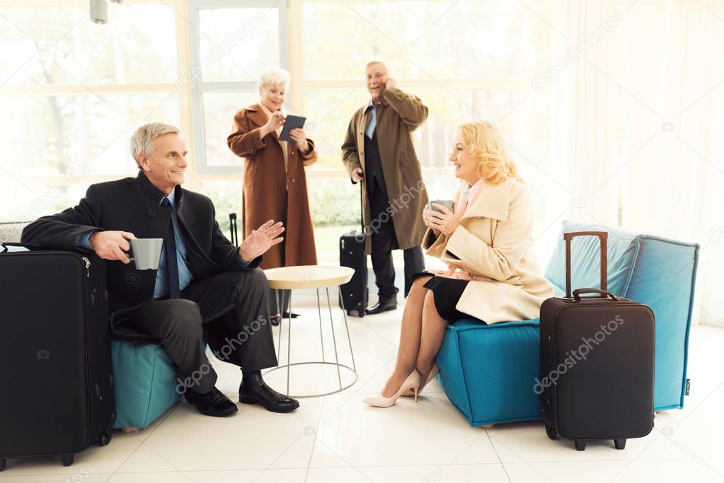 Elderly couple in the airport lounge. They are in the waiting room with suitcases.