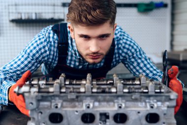 Genç bir adam bir benzinlikte çalışır. Tamirci arabanın tamirinde devreye girer.