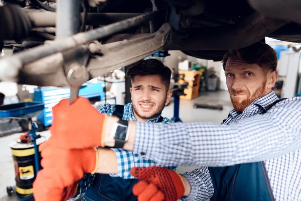 Vader en zoon werken op de auto-service. Twee monteurs werken met de gegevens van de auto. — Stockfoto