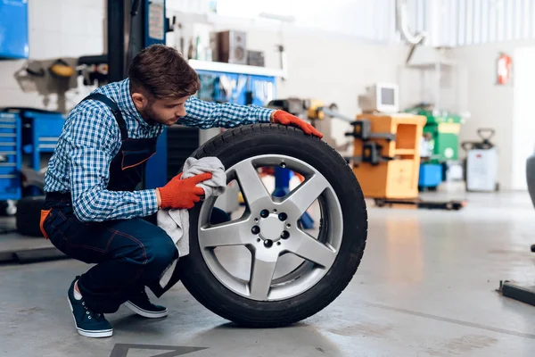 若い男は、サービス ステーションで動作します。メカニックが車の修理に従事しています。. — ストック写真