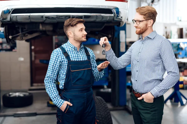 Mannen ger sin bil till tjänsten auto. Klienten skickar nycklarna till bilen till mekaniker — Stockfoto