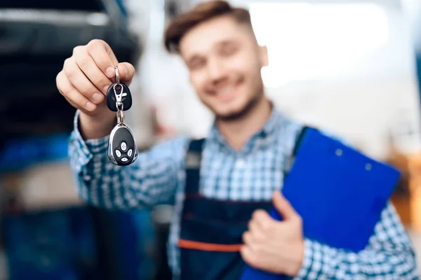 The man takes his car from the auto service. The mechanic transfers the car keys to the customer — Stock Photo, Image