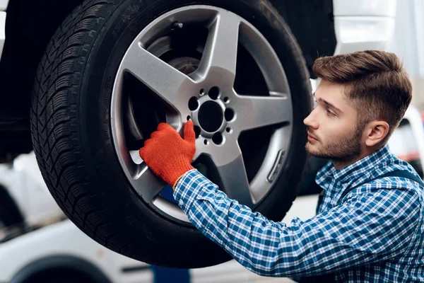 A young man works at a service station. The mechanic is engaged in repairing the car — Stock Photo, Image