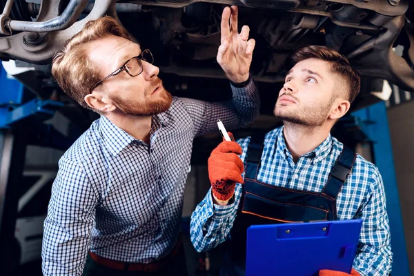 Людина на результат роботи механіка. Клієнт оцінює ремонт автомобіля механіком — стокове фото