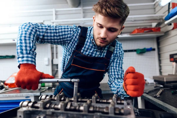 A young man works at a service station. The mechanic is engaged in repairing the car. — Stock Photo, Image