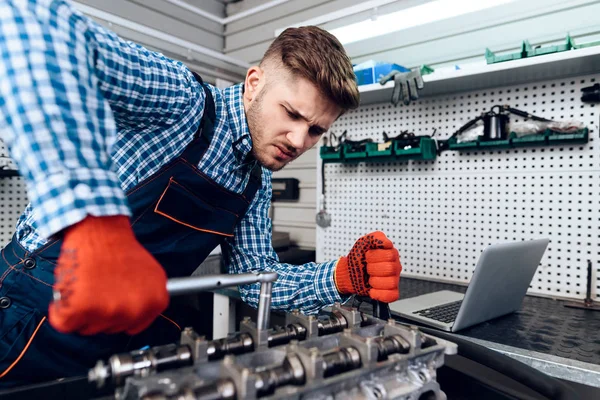 Un joven trabaja en una estación de servicio. El mecánico se dedica a reparar el coche . — Foto de Stock