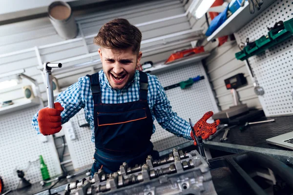Een jonge man werkt bij een tankstation. De monteur houdt zich bezig met het repareren van de auto. — Stockfoto