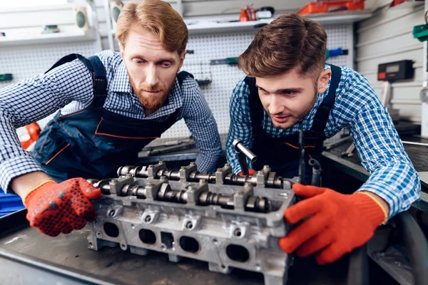 Vader en zoon werken op de auto-service. Twee monteurs werken met de gegevens van de auto. — Stockfoto