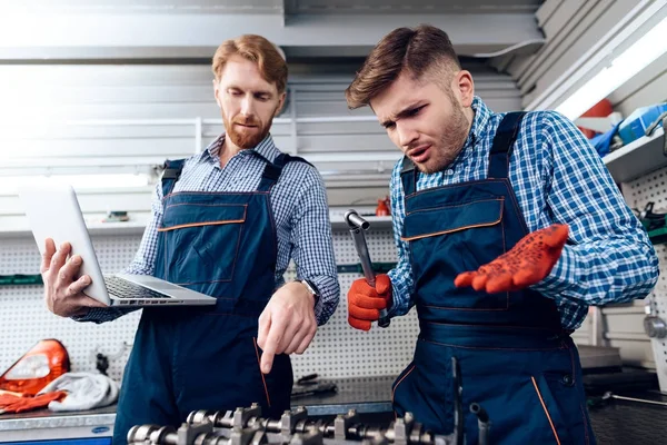 Padre e hijo trabajan en el servicio de autos. Dos mecánicos trabajan con los detalles del coche . — Foto de Stock