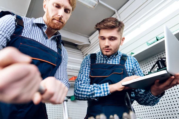 Vader en zoon werken op de auto-service. Twee monteurs werken met de gegevens van de auto. — Stockfoto