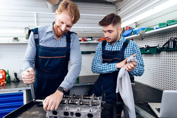 Padre e hijo trabajan en el servicio de autos. Dos mecánicos trabajan con los detalles del coche . — Foto de Stock