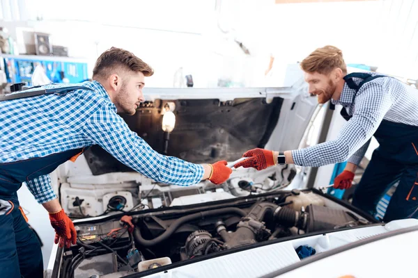 Padre e hijo trabajan en el servicio de autos. Dos mecánicos trabajan con los detalles del coche . — Foto de Stock