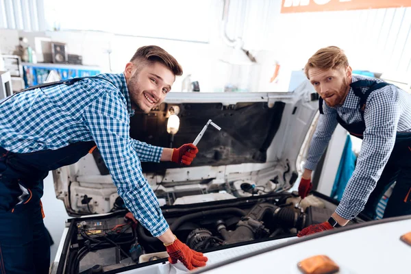 Padre e hijo trabajan en el servicio de autos. Dos mecánicos trabajan con los detalles del coche . —  Fotos de Stock