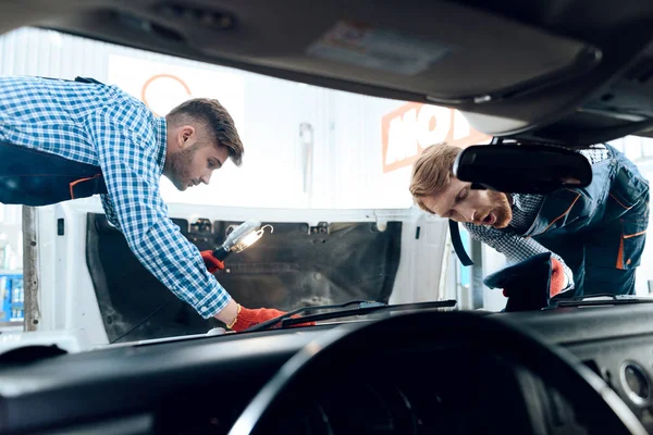 Father and son work at the auto service. Two mechanics work with the details of the car. — Stock Photo, Image